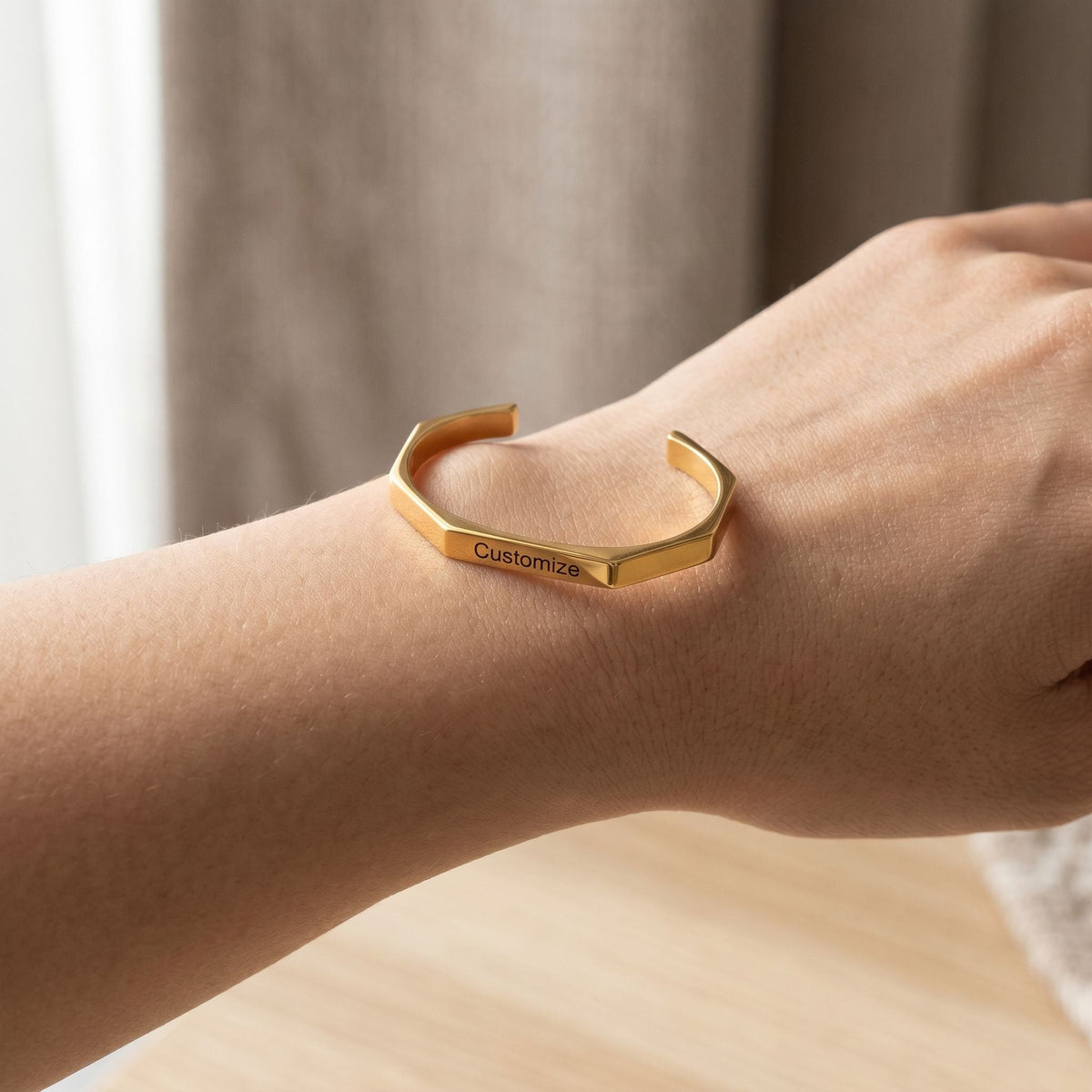 Delicate hexagon-shaped engraved karha bracelet resting on a wrist with natural light highlighting the engraved name.