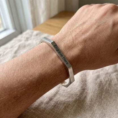 Close-up of model's wrist showcasing designer engraved hexagon karha bracelet in natural lighting with subtle surface highlights.